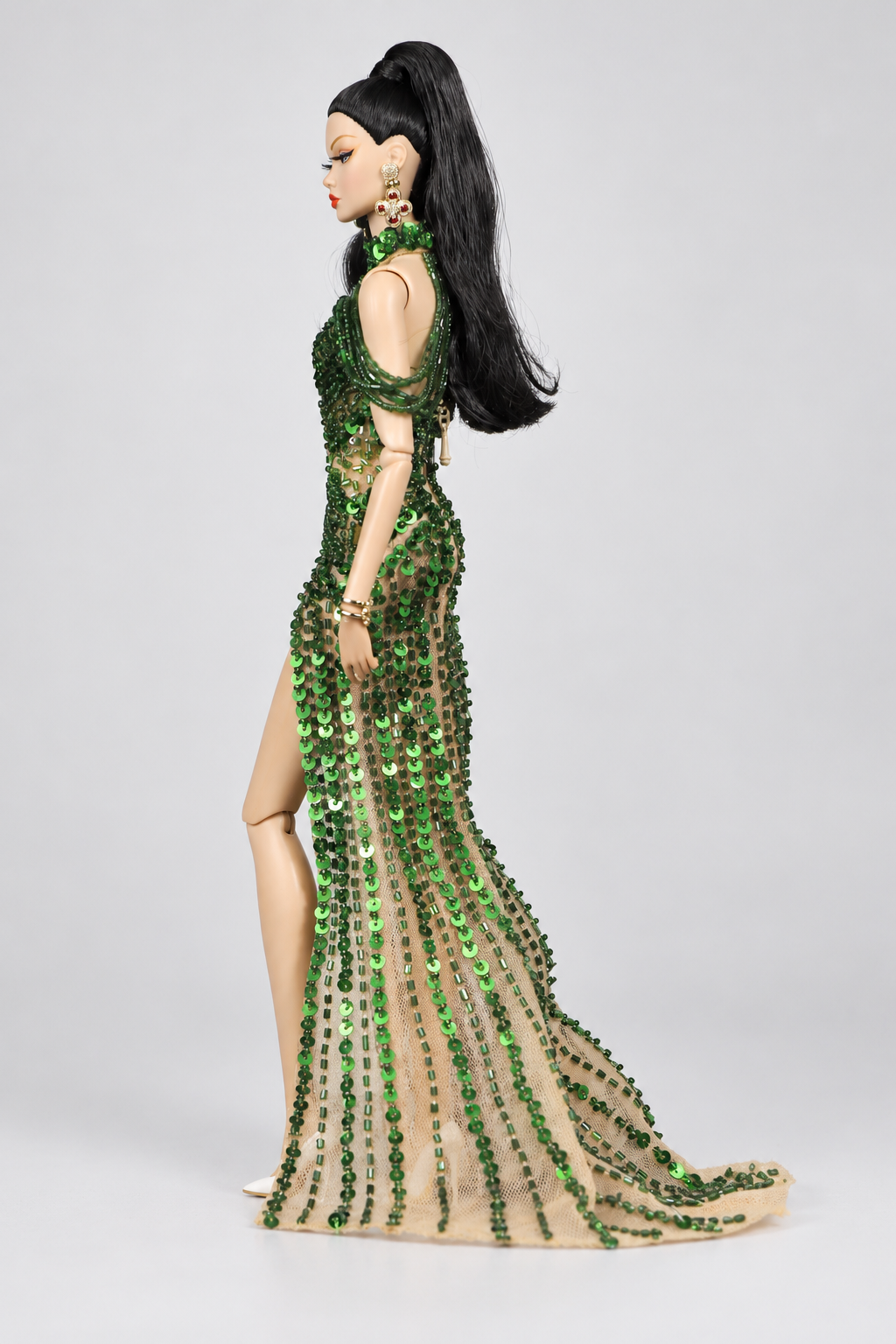 Side view of the emerald doll gown showing curved green bead rows over the hips and vertical decoration down the sheer train.