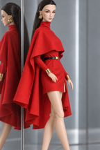 Three-quarter view of LE SALON No. 01, showing the short red skirt, long sleeves and draped cape panels.