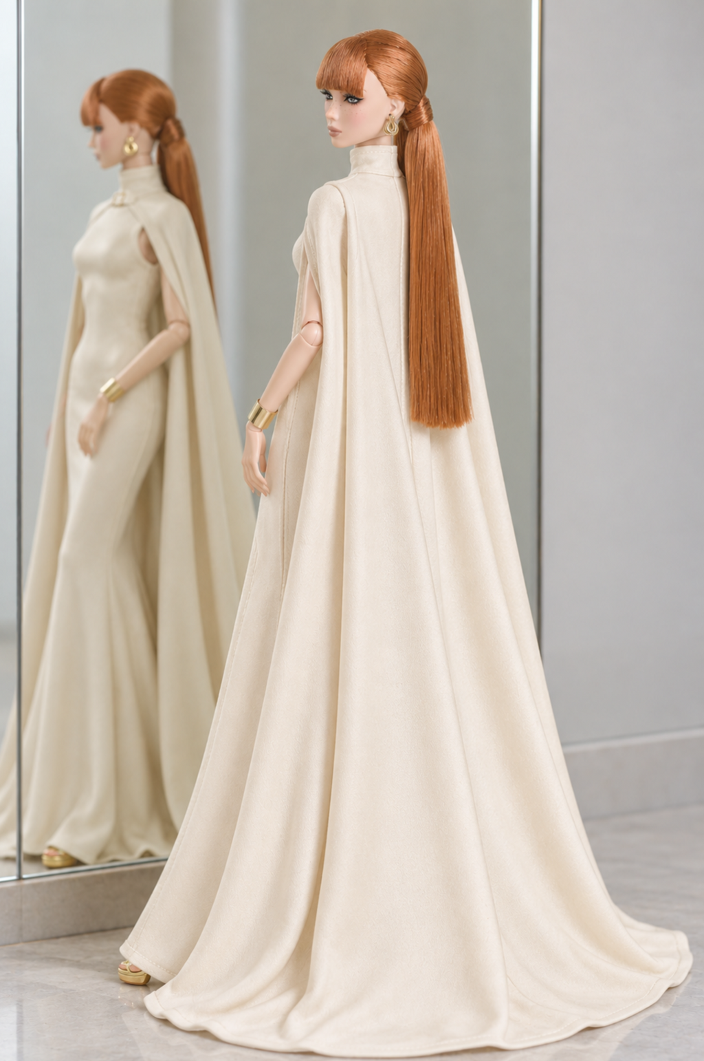 Back view of LE SALON No. 02 ivory cape gown, with long cape panels spreading into soft folds at floor level.
