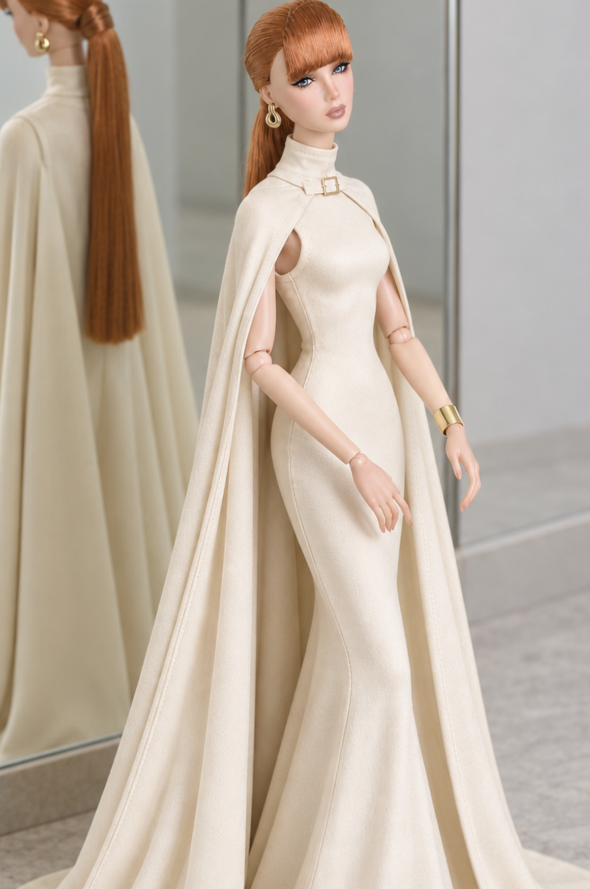 Closer view of LE SALON No. 02 ivory gown, showing the fitted bodice, gold-tone collar buckle and draped cape.