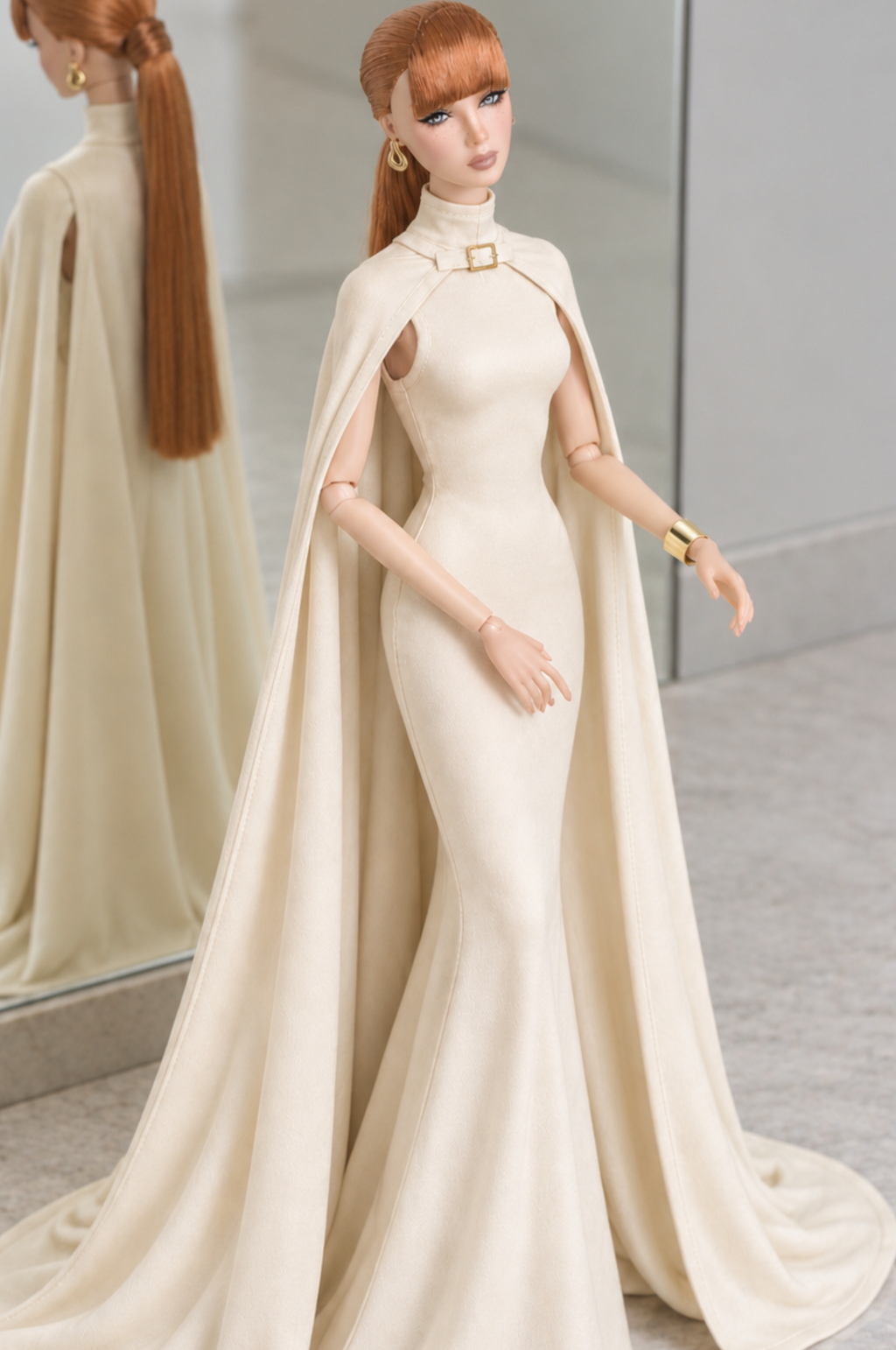 Front three-quarter view of LE SALON No. 02 ivory silk jersey gown with a gold-tone collar buckle and long flowing cape.