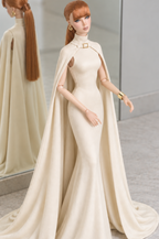Front three-quarter view of LE SALON No. 02 ivory silk jersey gown with a gold-tone collar buckle and long flowing cape.