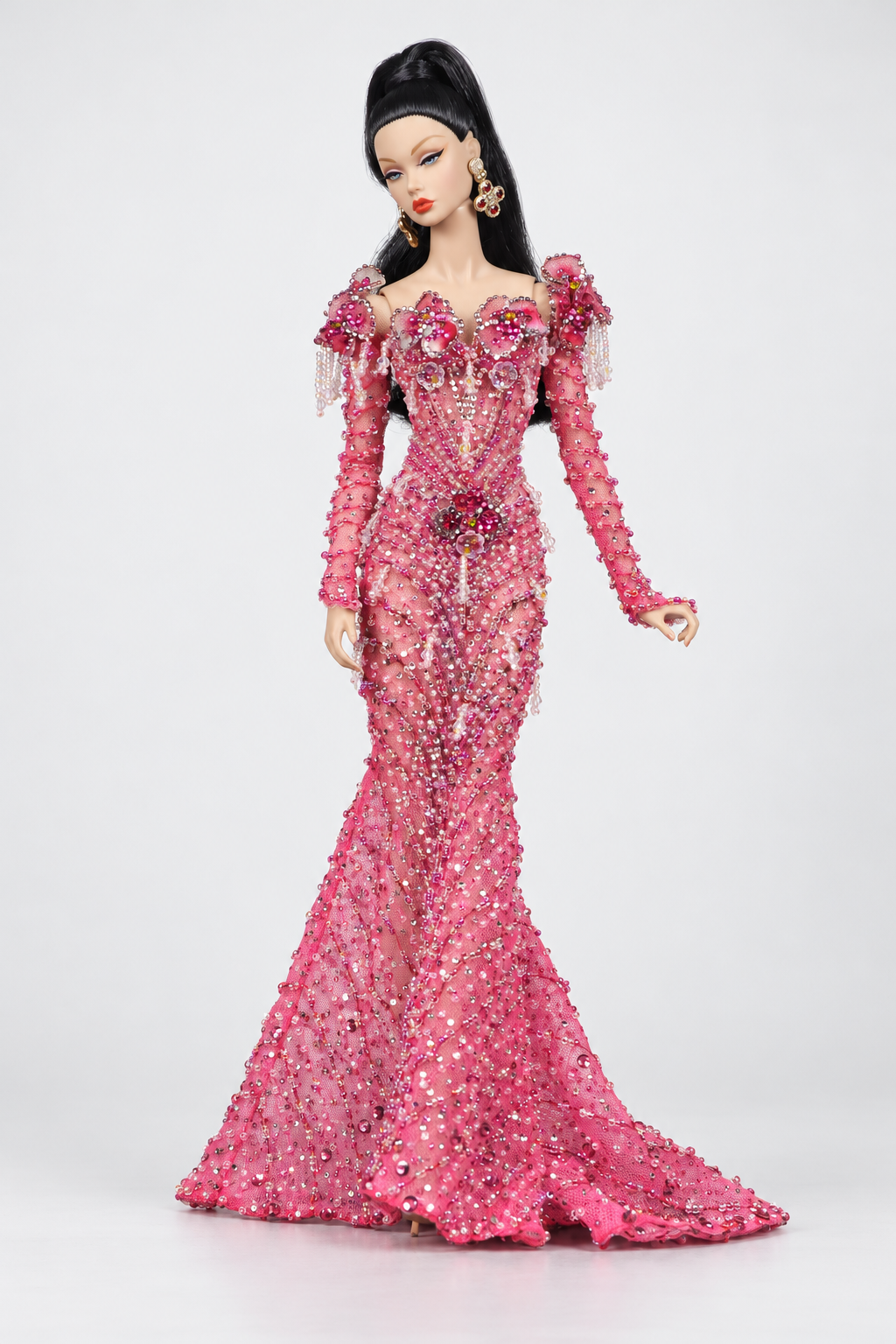 Full-length fashion doll in a pink embellished mermaid gown with floral shoulder accents, long sleeves and a trailing hem.