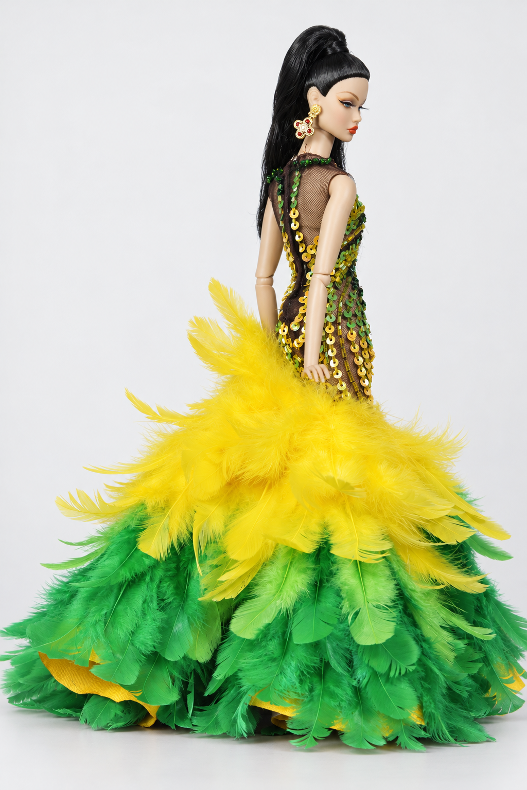 Side three-quarter view showing the fitted embellished upper gown and layered yellow and green feather flare.