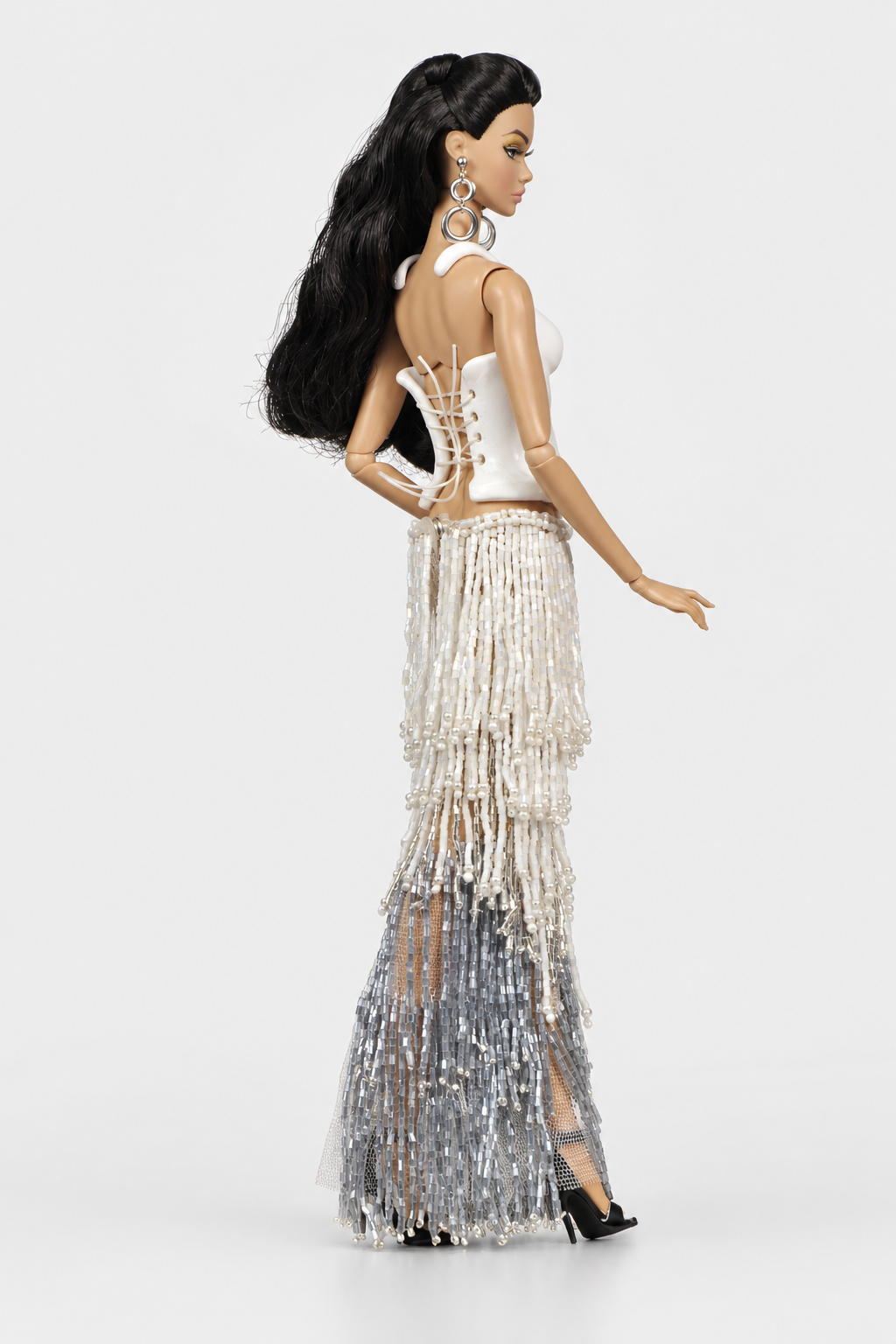 Rear three-quarter view showing the white bodice's crisscross back lacing and cascading ivory and silver bead strands.